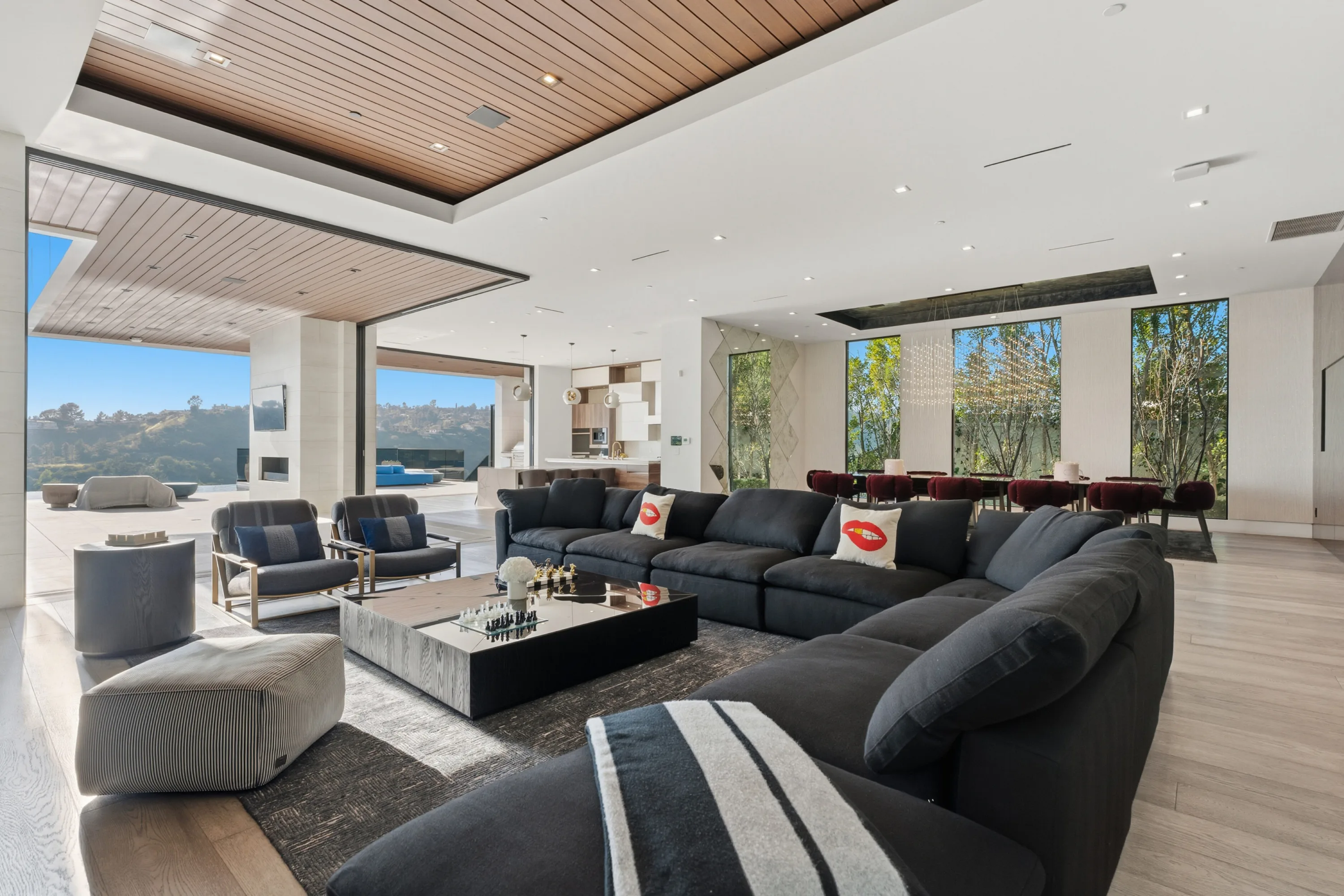 Family room with oversized charcoal sectional and chess set, sliding walls opened to the terrace and canyon ridgeline