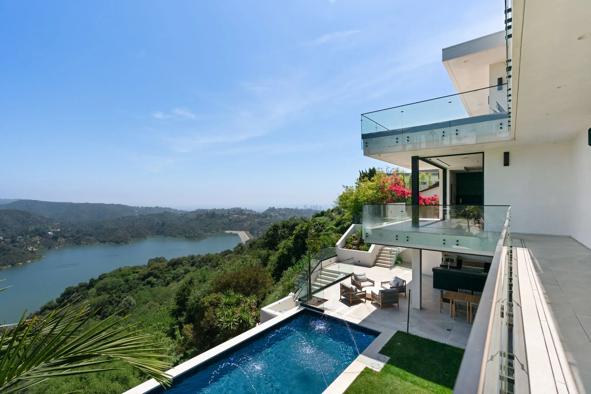 Terrace view down to the pool and shaded lounge deck, with the Bel Air Reservoir and green canyon beyond