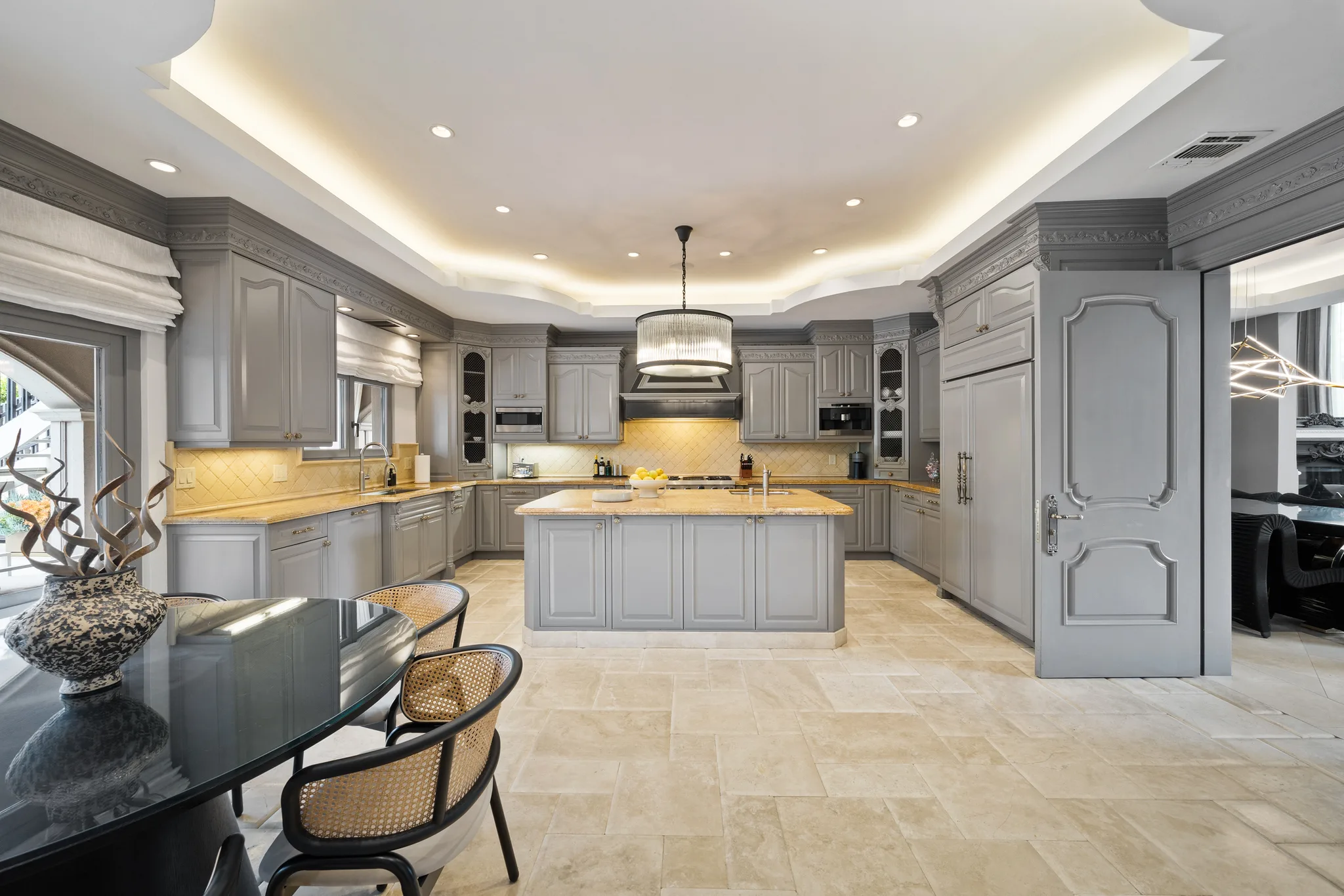 Wider kitchen view with travertine floors, central prep island and casual glass breakfast table