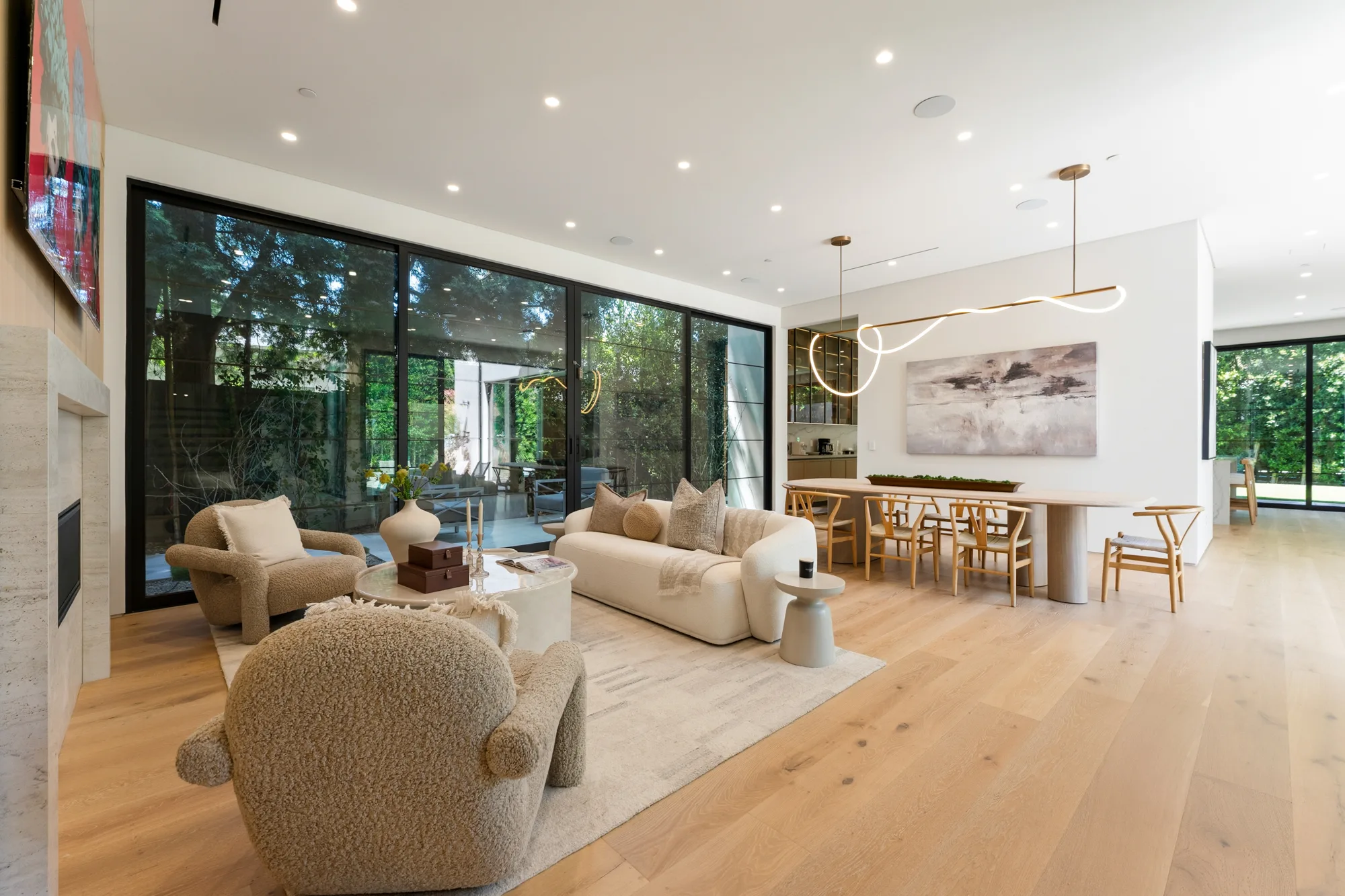 Open living and dining room with boucle armchairs, sculptural chandelier and sliding glass to the courtyard