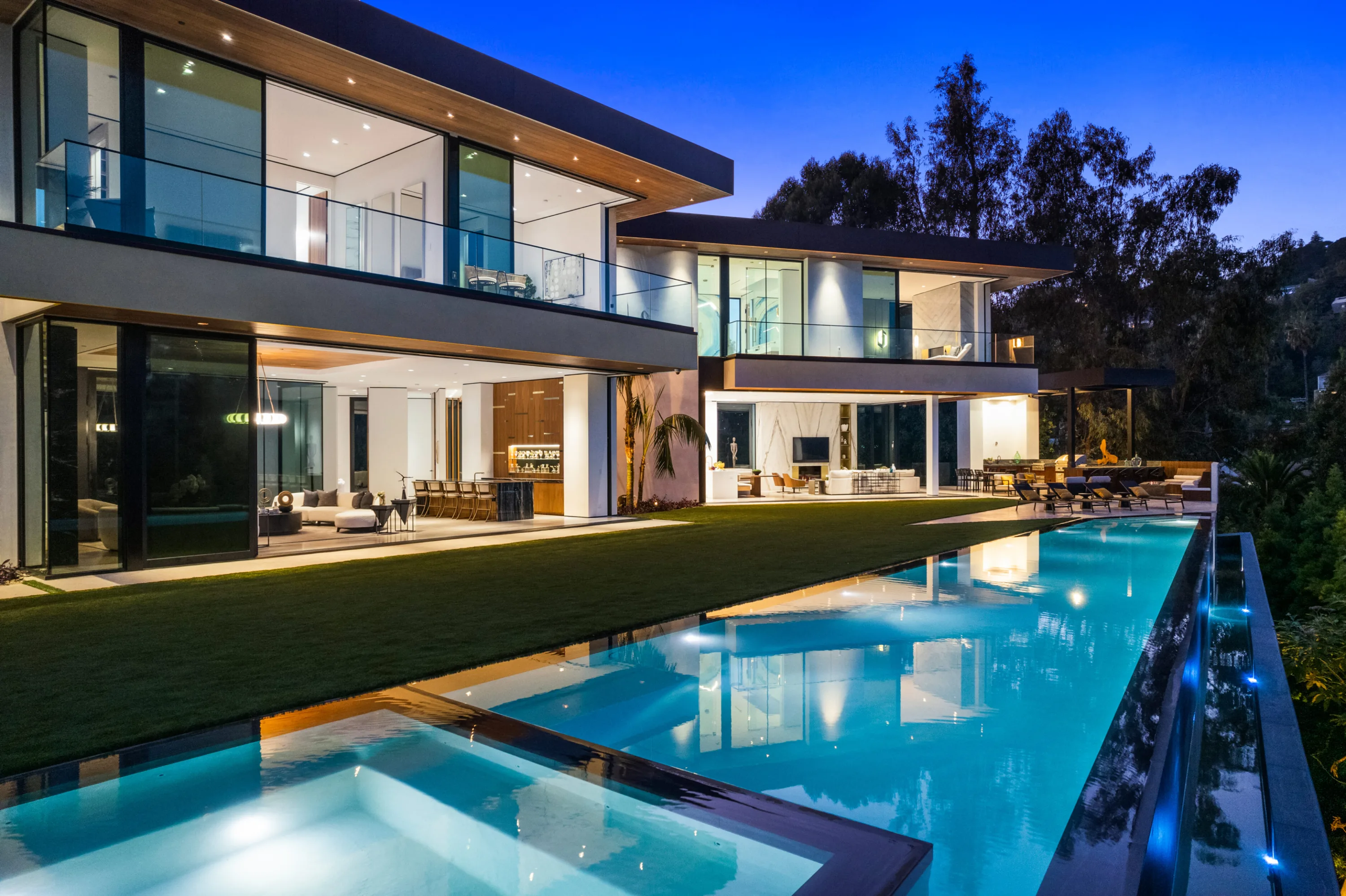Poolside view along the water to the indoor-outdoor bar lounge and covered fire-pit seating
