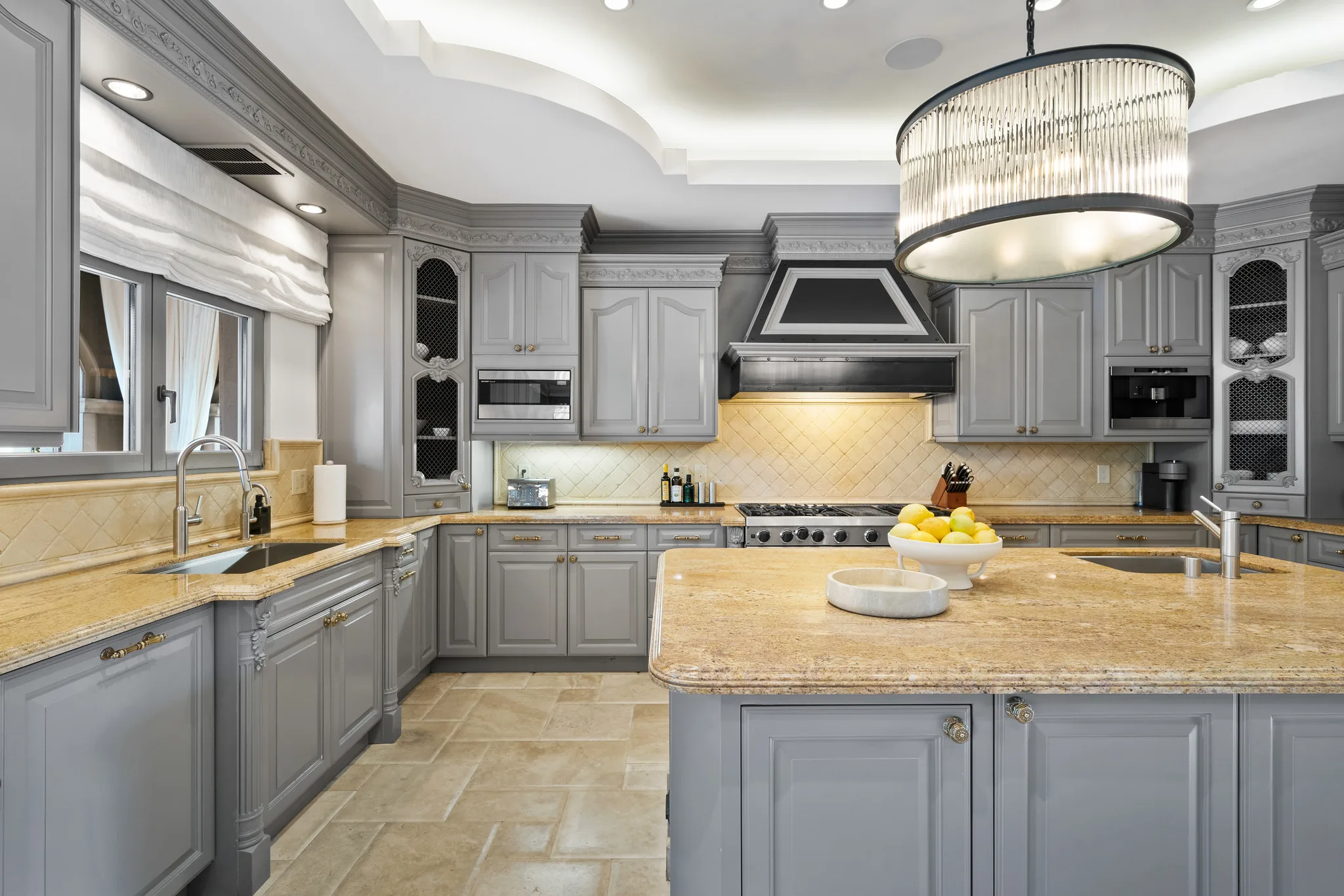 Chef's kitchen with granite island, range under a steel hood and drum chandelier overhead