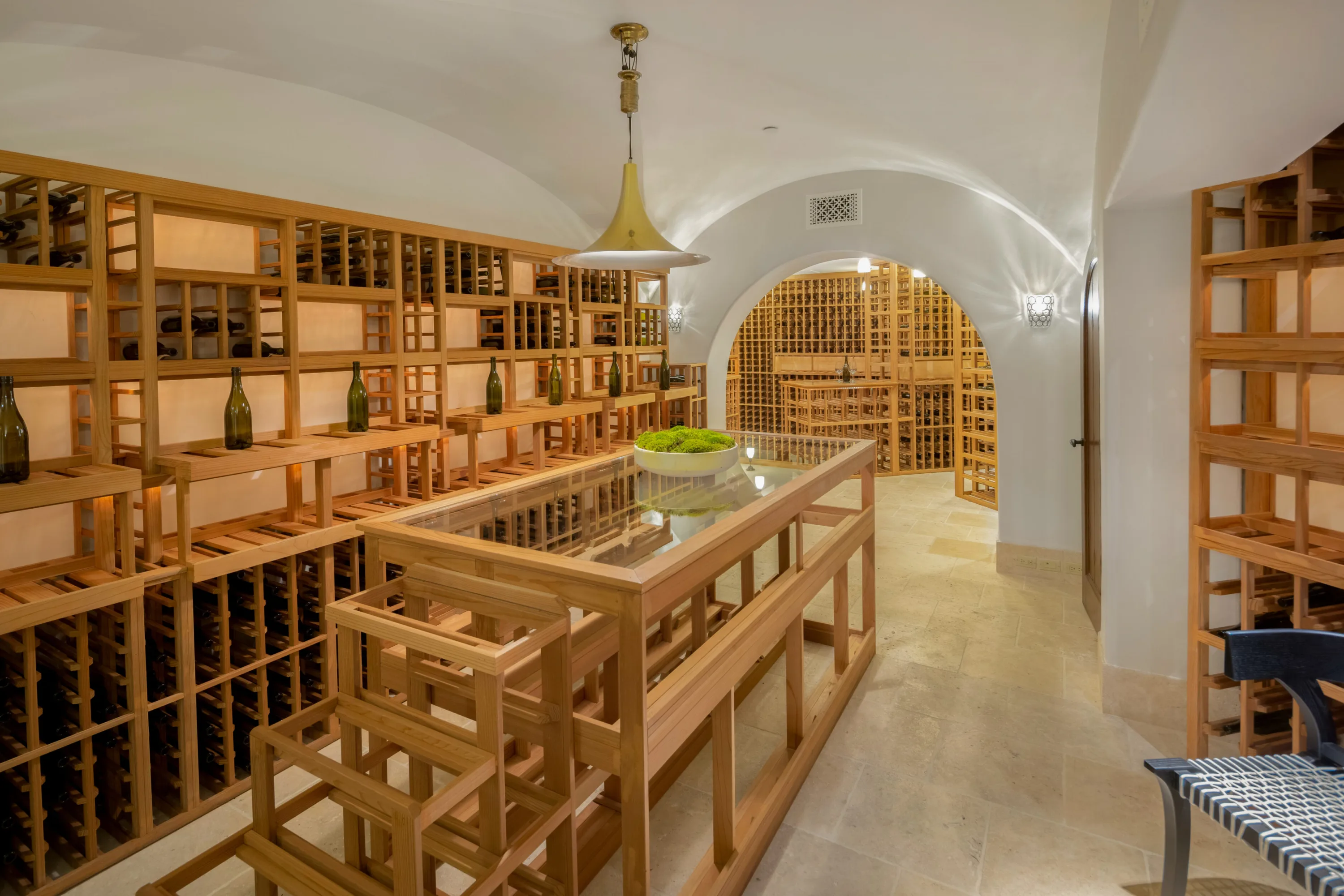 Barrel-vaulted wine cellar lined with timber racking and a glass-topped tasting island