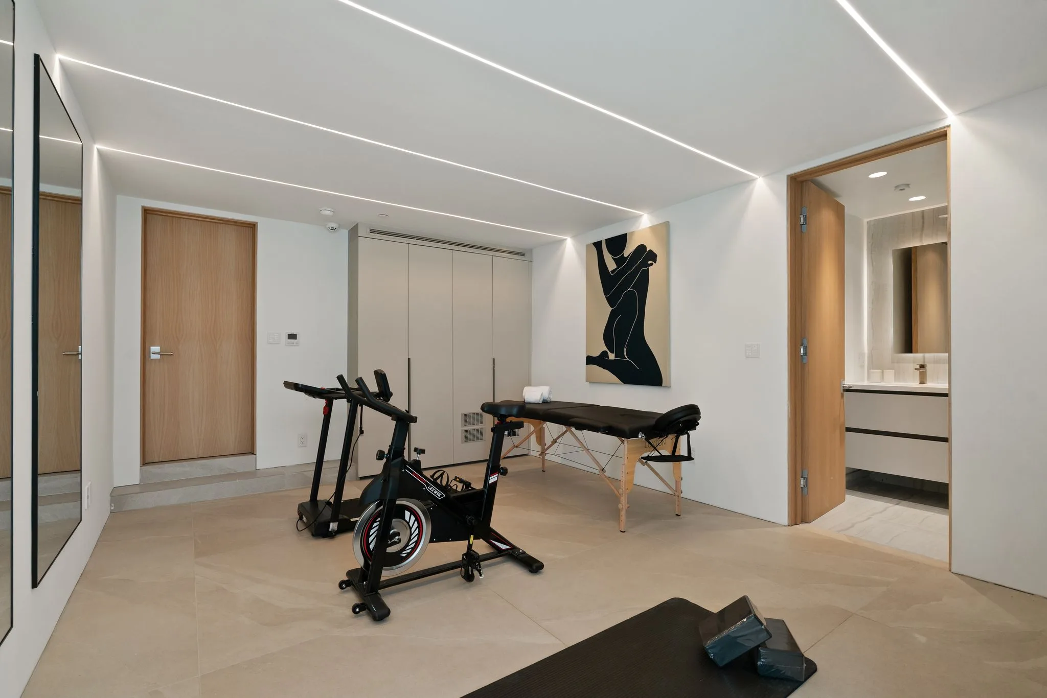 Wider view of the fitness room, mat and yoga blocks in the foreground and an ensuite bathroom beyond