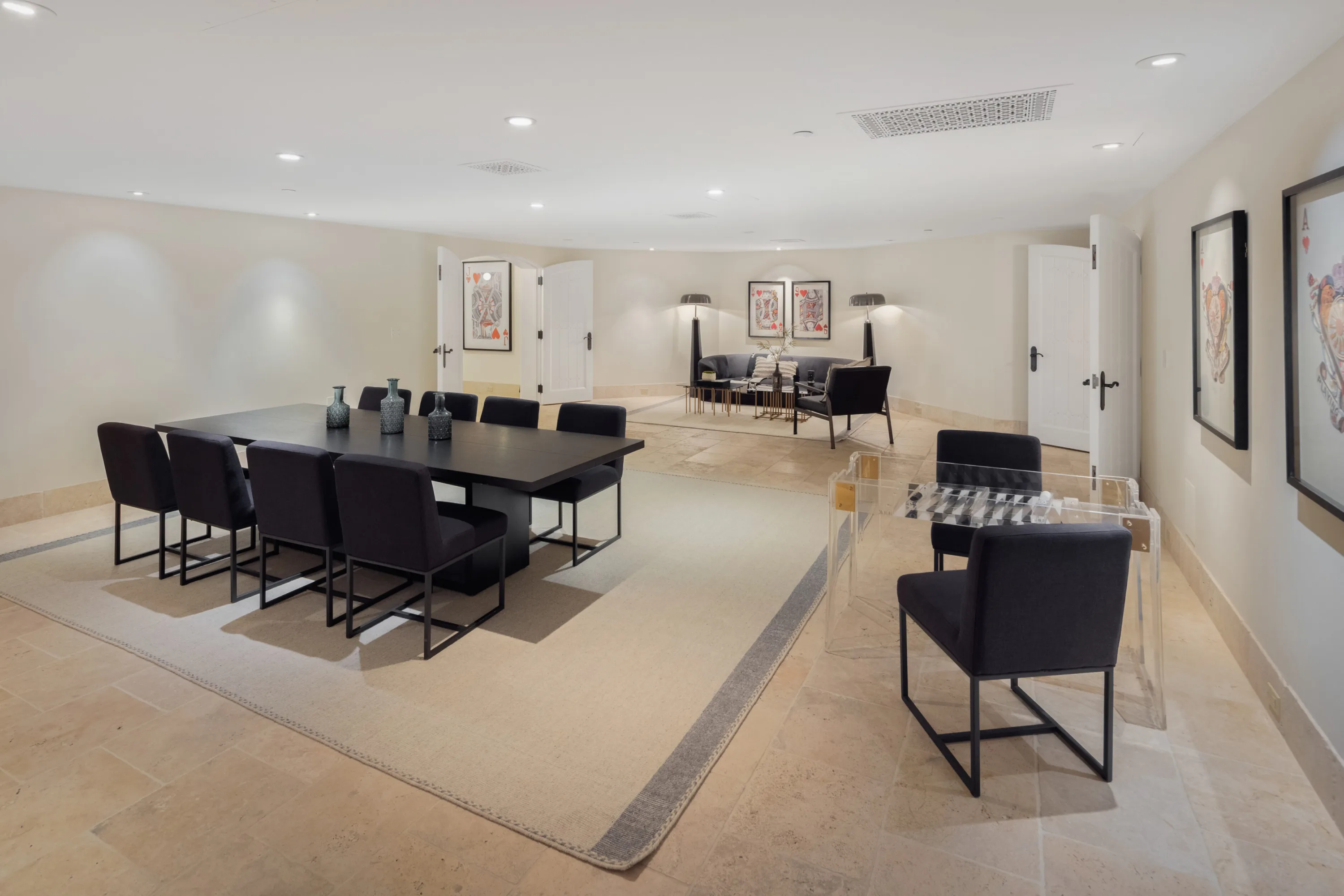 Card room with long black table for eight, acrylic games table and playing-card artwork on the walls