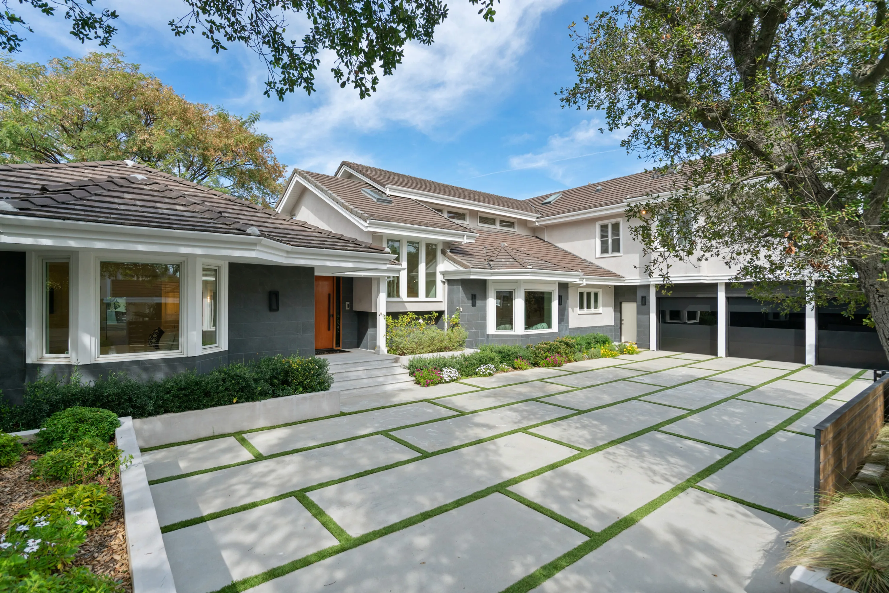 Gated Brentwood frontage with grass-seamed motor court, orange front door and three-car garage
