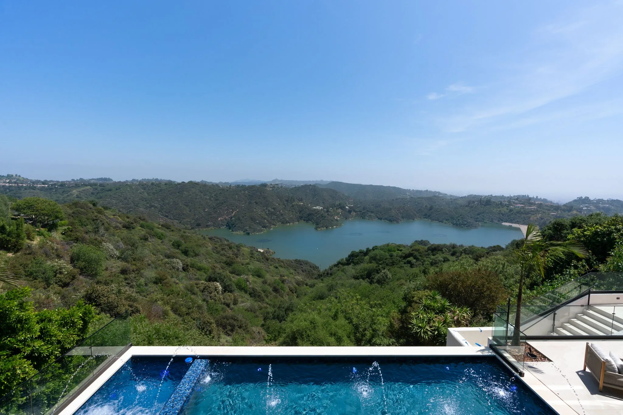 Glass-edged pool with water jets looking straight out over the reservoir and wooded hillsides