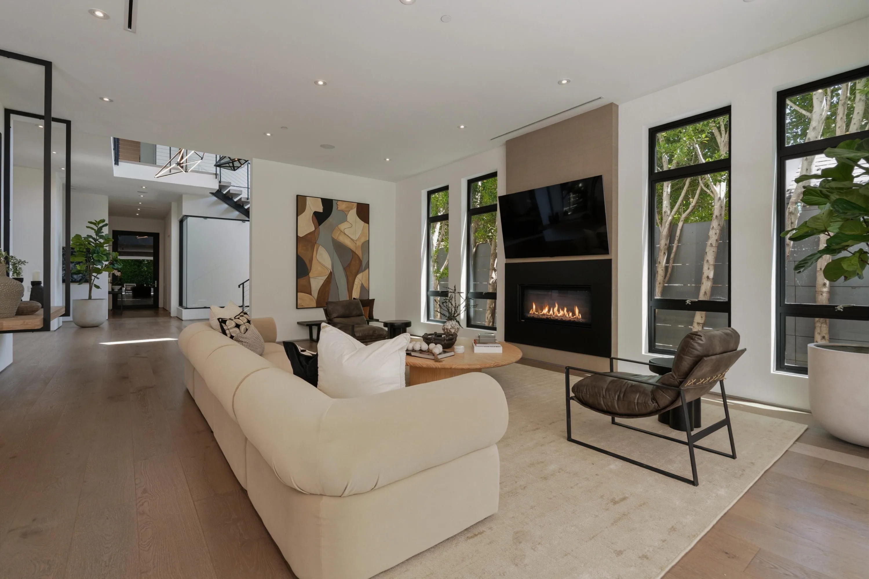 Double-height living area with floating staircase, fireplace seating and oak floors running to the entry