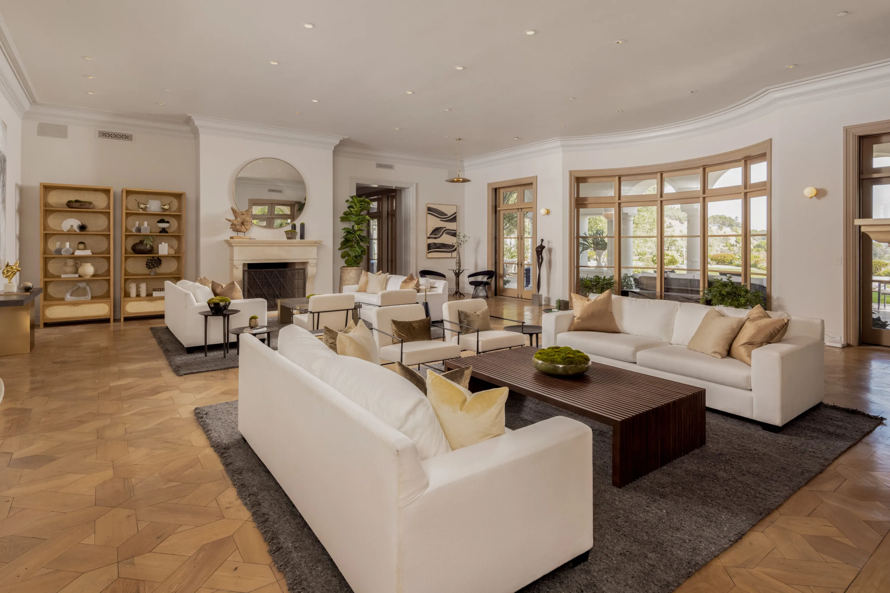 Fireplace end of the living room, parquet floors, open shelving and French doors to the colonnaded terrace