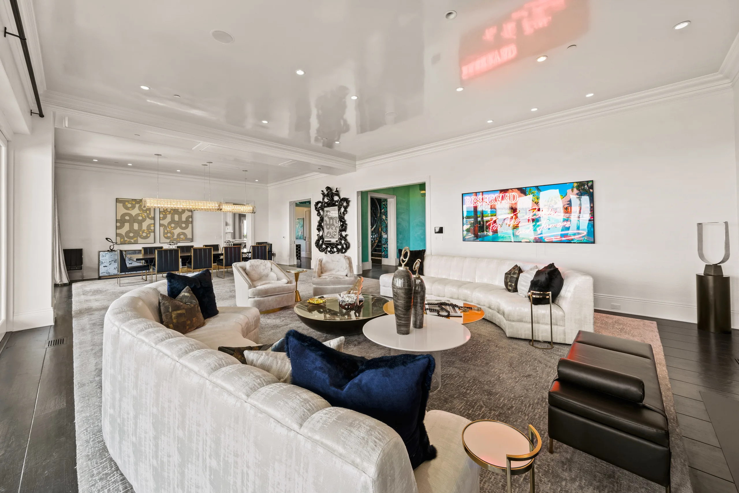 Double seating groups and dining table beyond, under a high-gloss ceiling; wall art reads "RESERVED"