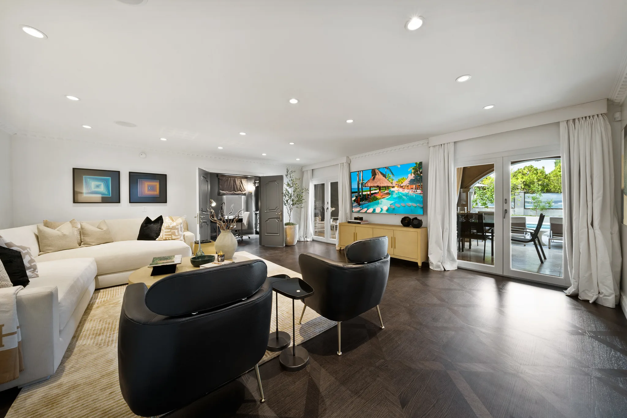 Media lounge with big-screen TV and French doors opening to the pool terrace