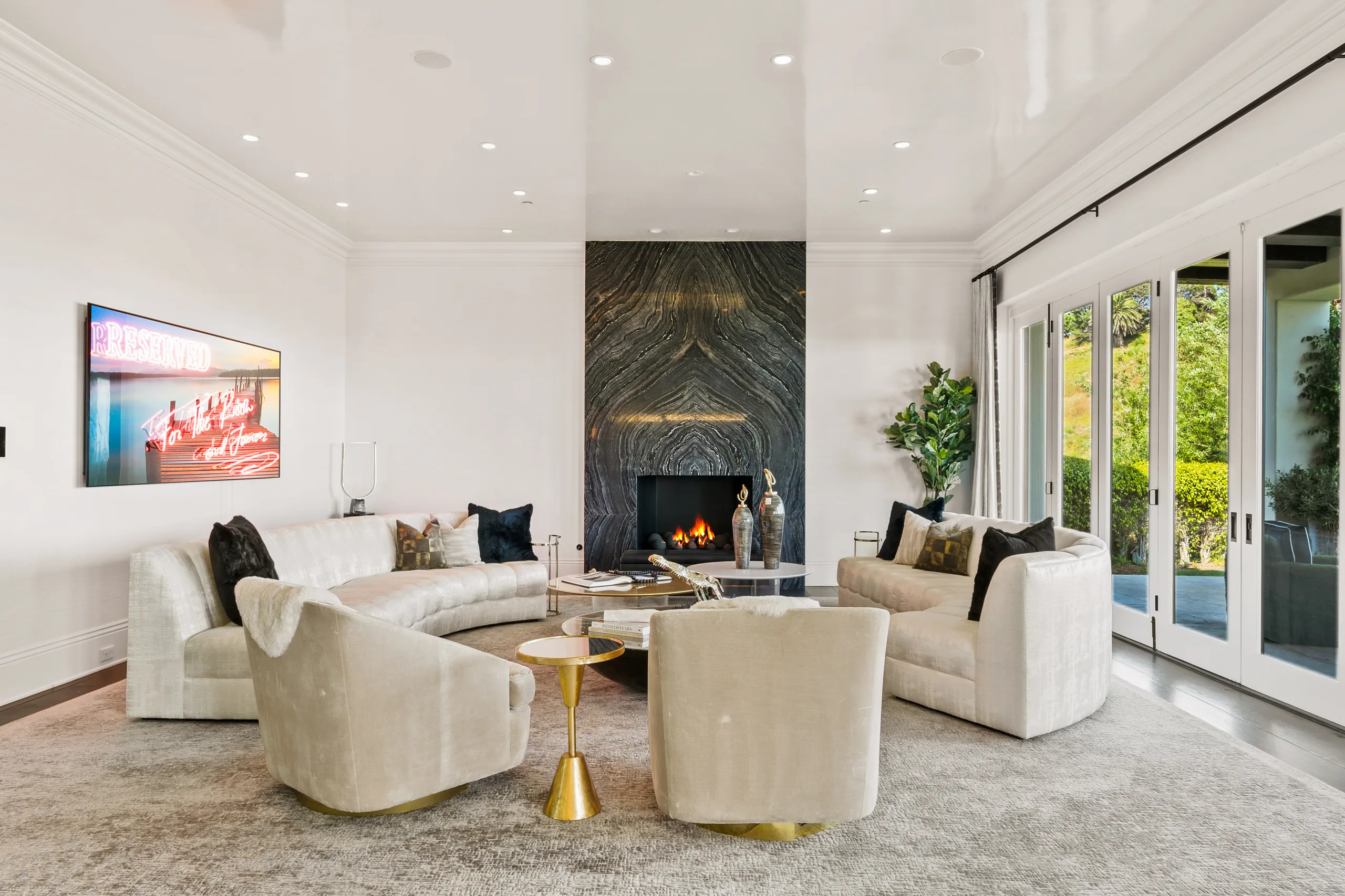 Lounge anchored by a dramatic veined stone fireplace, swivel chairs and neon "RESERVED" artwork