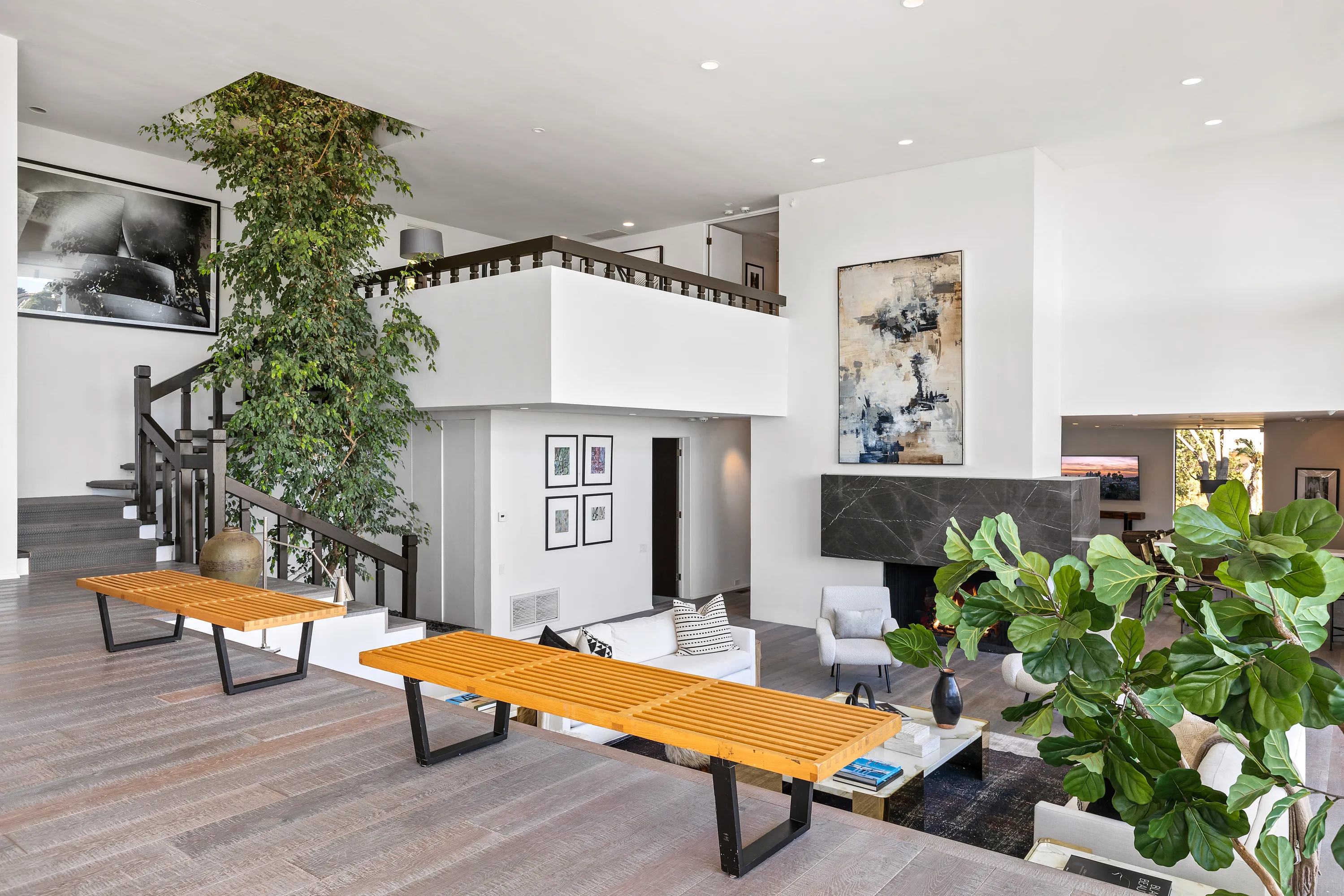 Entry hall seen from the living room, with slatted benches, indoor ficus and dark stone fireplace