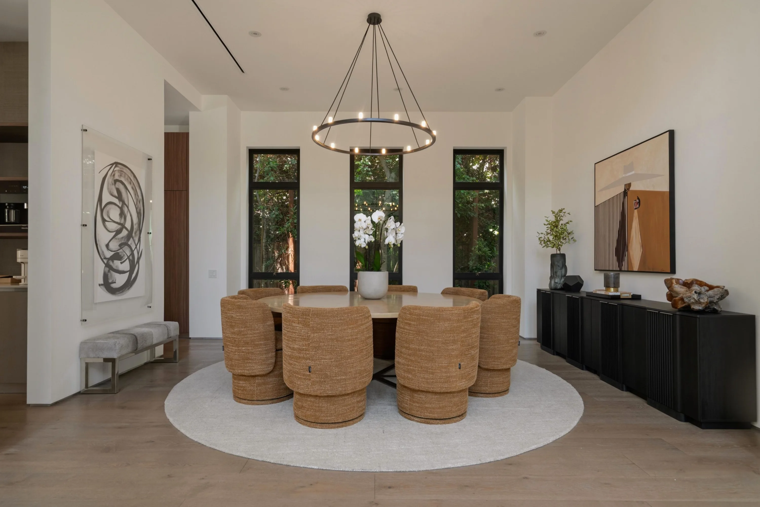 Formal dining room seating eight in woven chairs beneath a ring chandelier, orchids at the centre