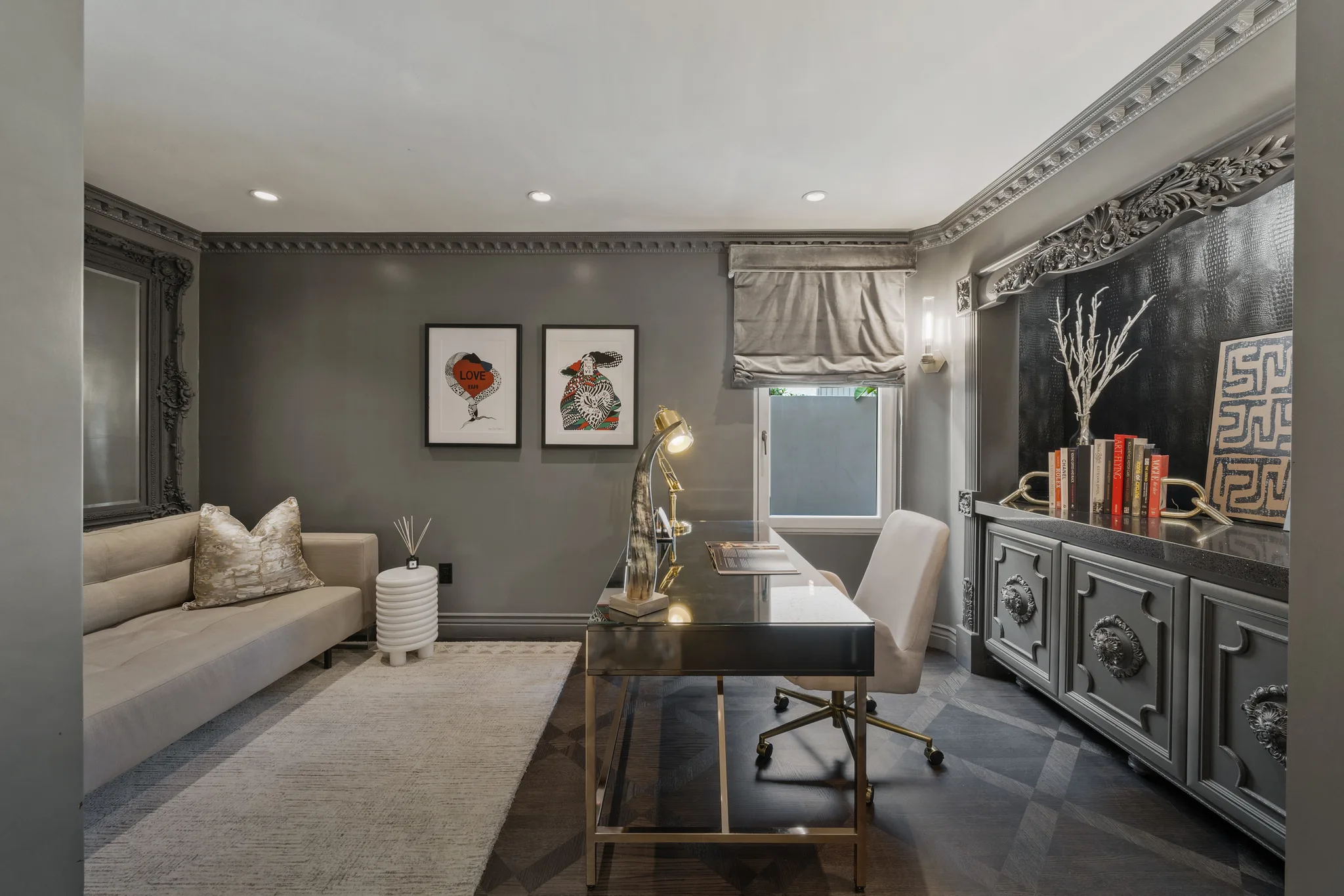 Home office in charcoal tones with brass-framed desk, daybed and carved sideboard