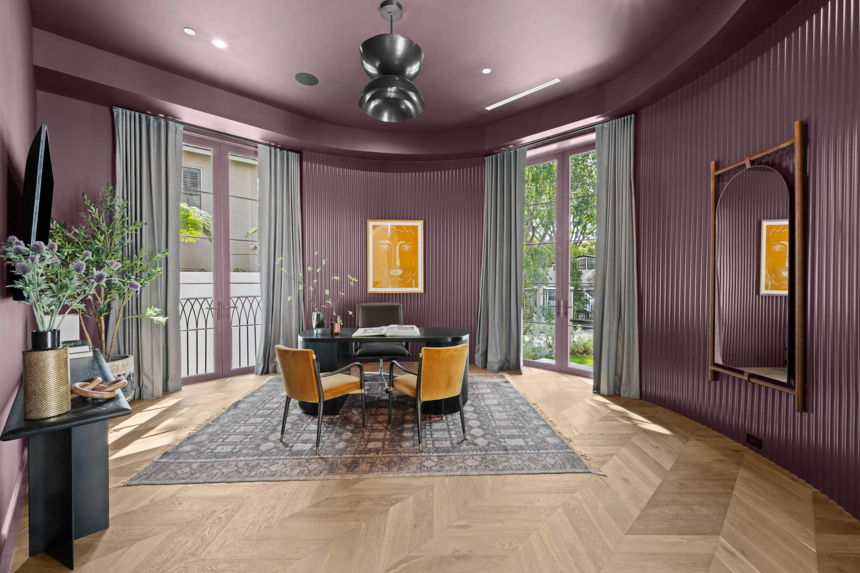 Plum-toned study with fluted walls, black desk, velvet chairs and French doors to the garden
