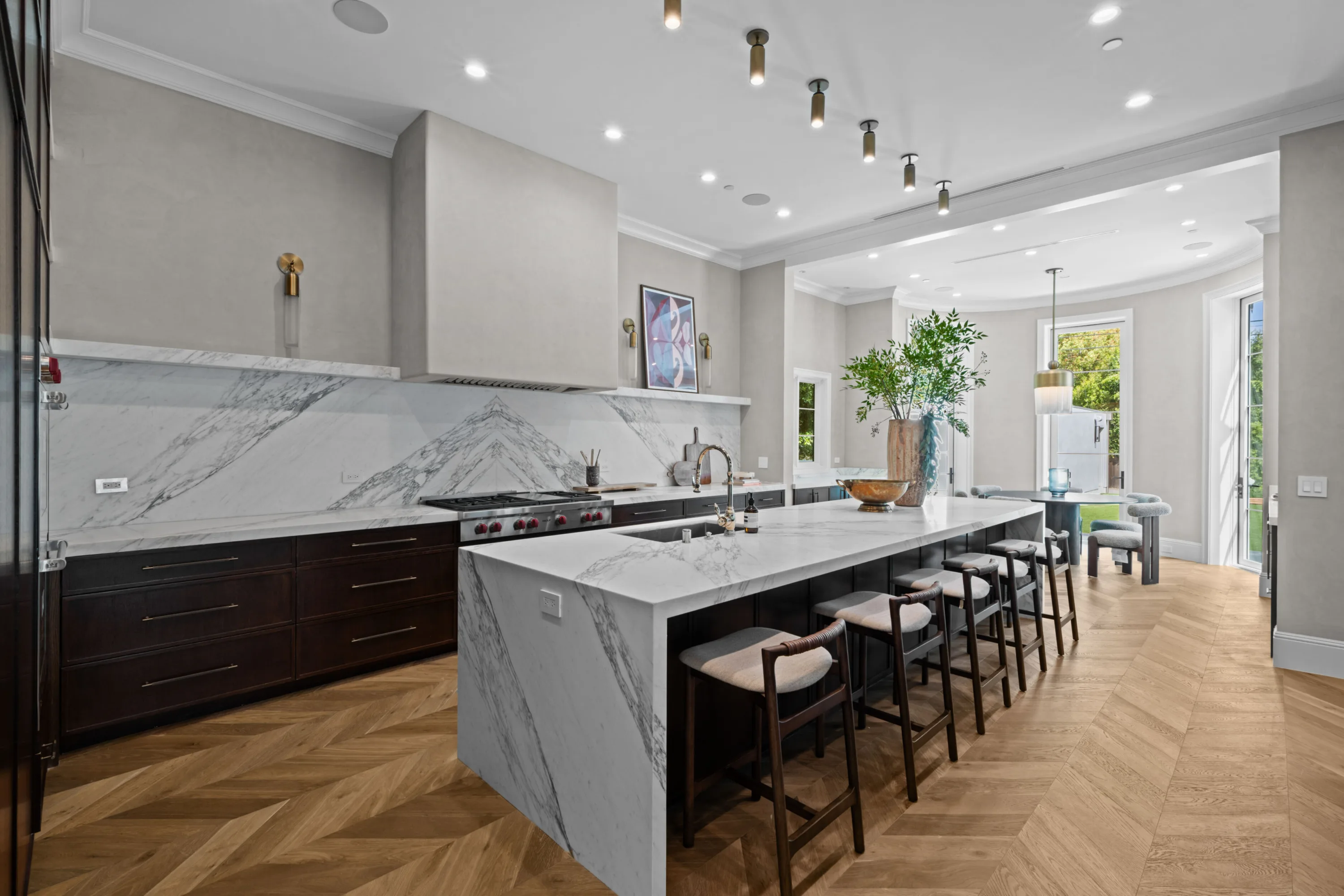 Chef's kitchen with waterfall marble island, seating for five, pro range and a breakfast nook beyond