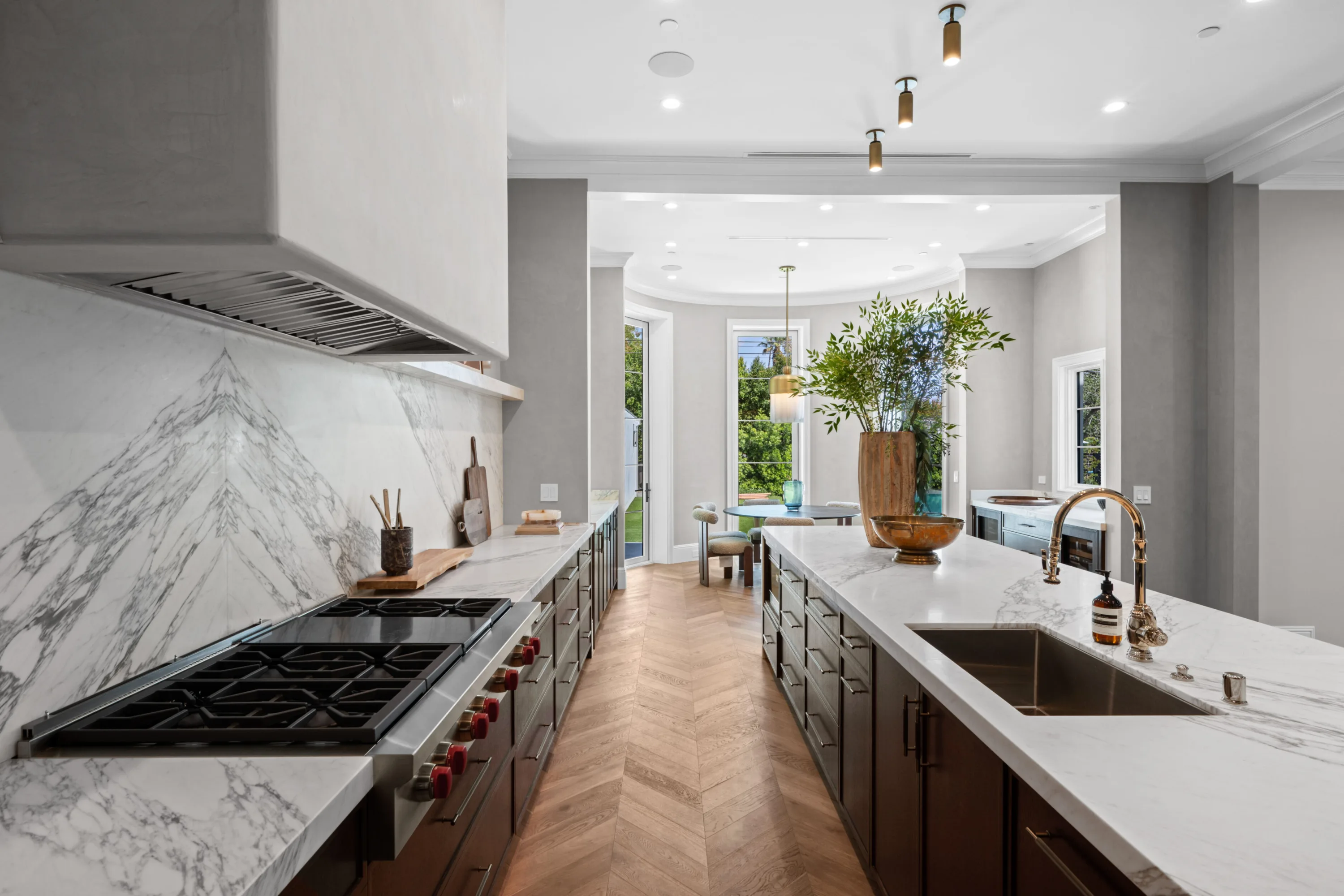 Six-burner range under a plaster hood, book-matched marble backsplash and a second prep sink across the island