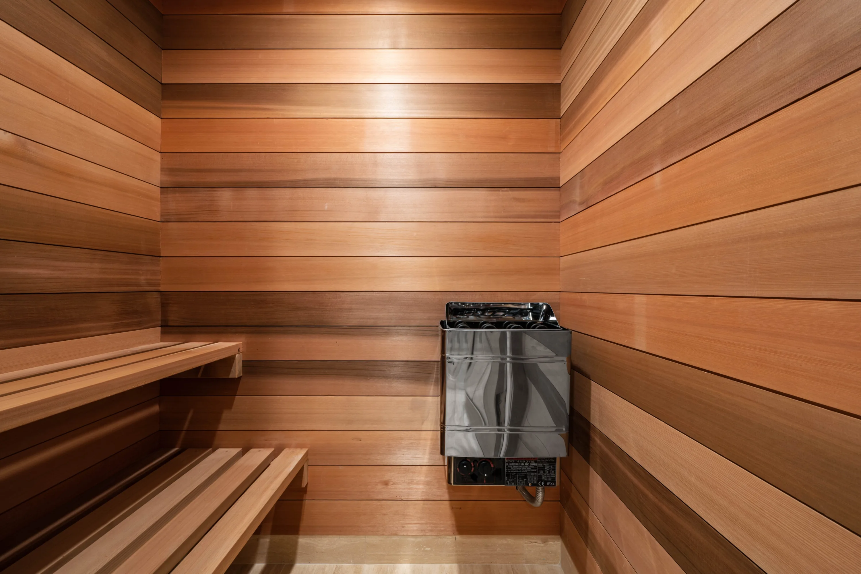 Cedar-lined sauna with tiered benches and a wall-mounted heater