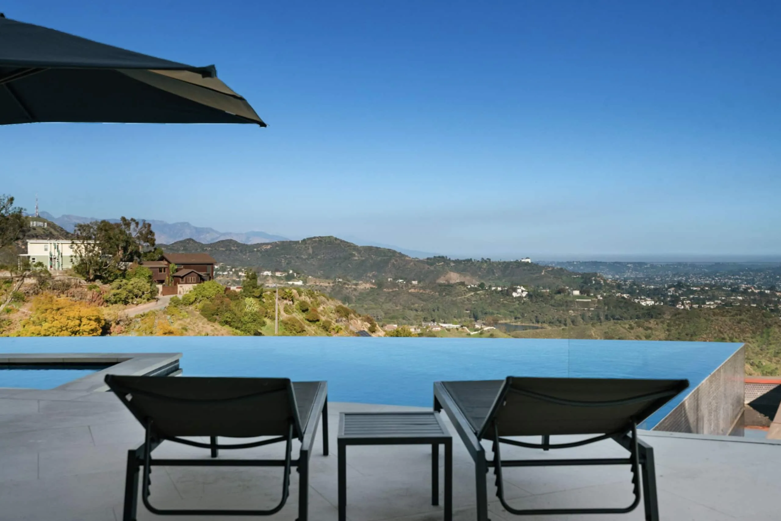 Sun loungers beside the infinity pool, water edge dissolving into the Hollywood Hills