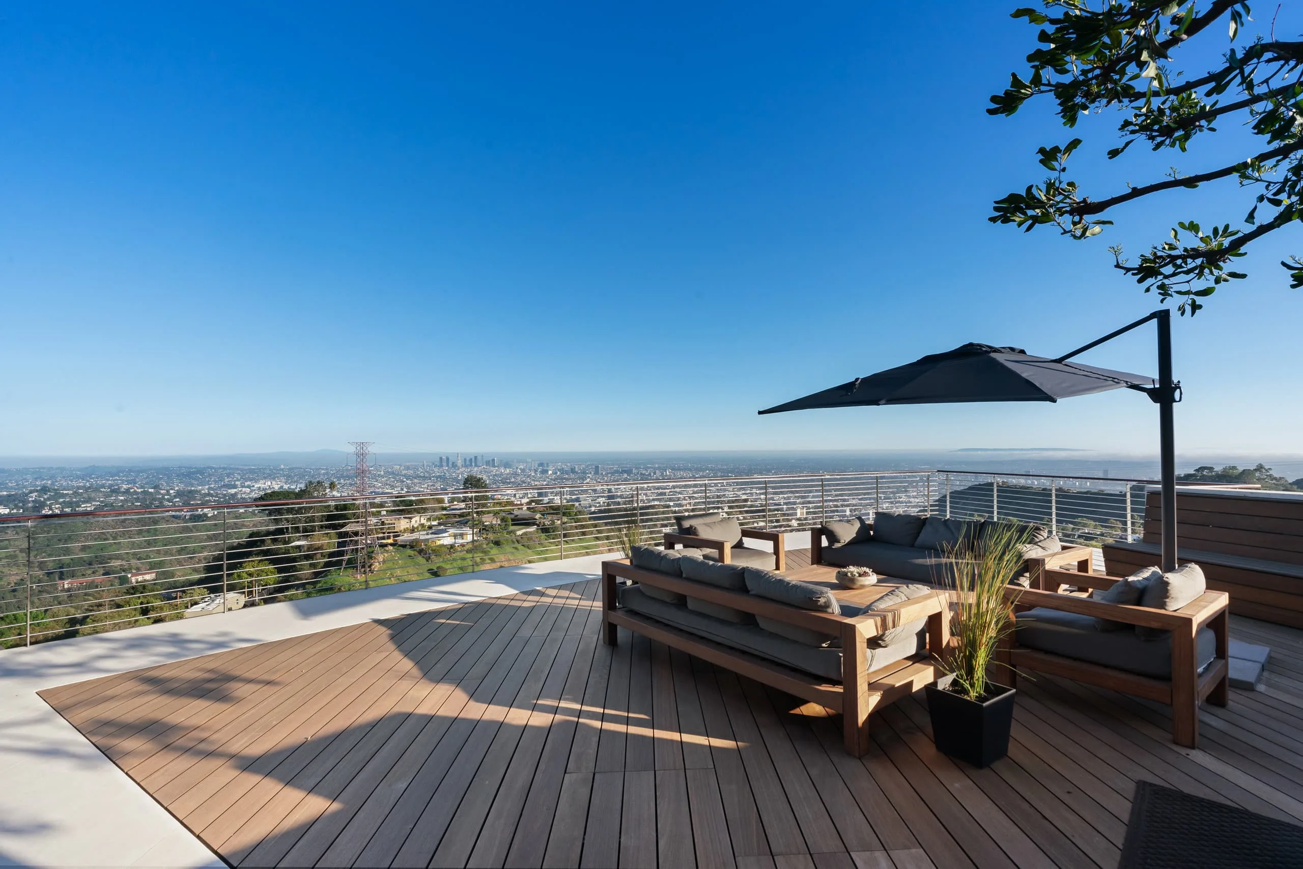 Timber roof deck with sectional sofas and cantilever parasol above the downtown LA skyline
