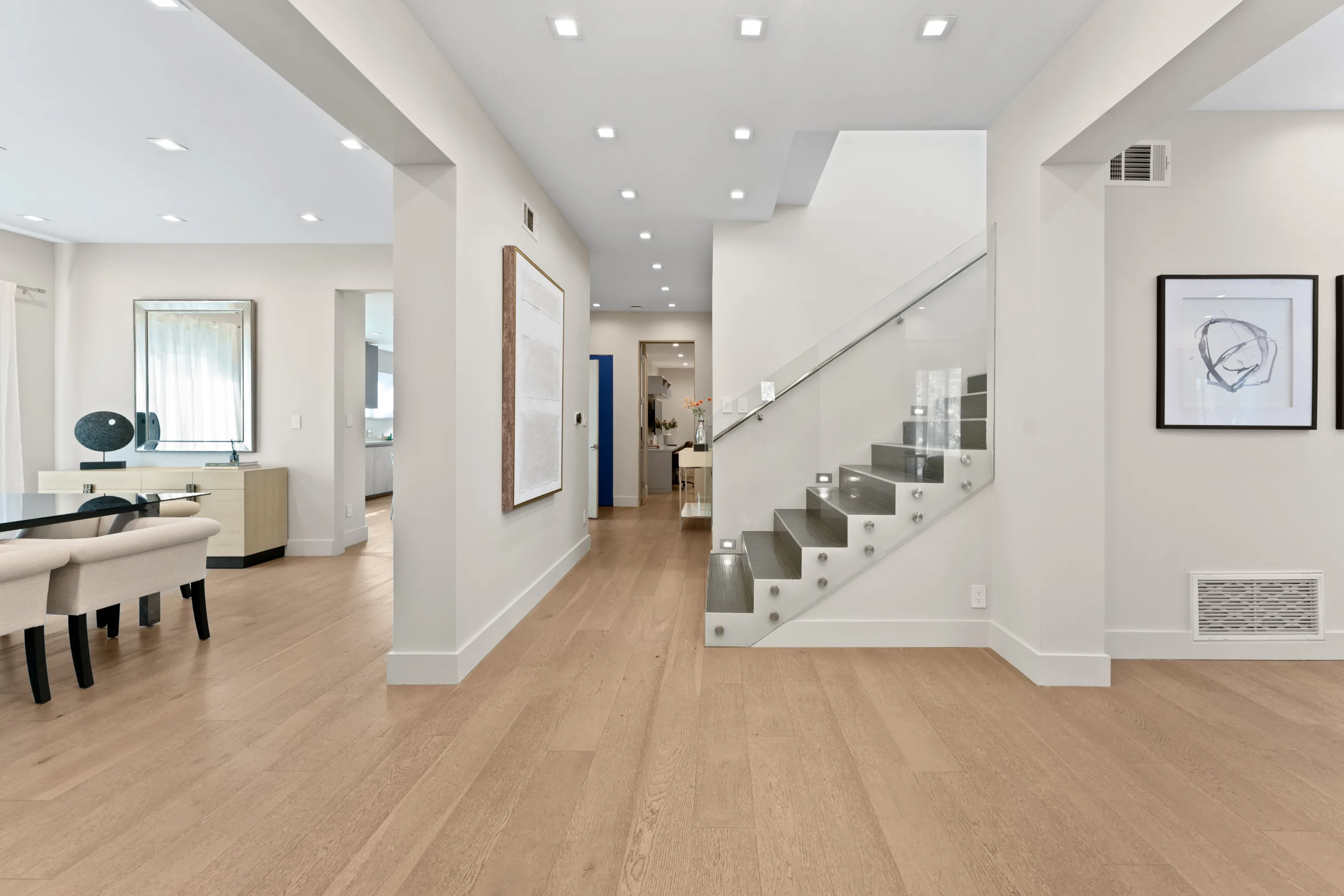 Modern staircase at Rodeo Villa, a luxury Beverly Hills vacation rental featuring glass railings, light wood floors, and elegant contemporary interiors.